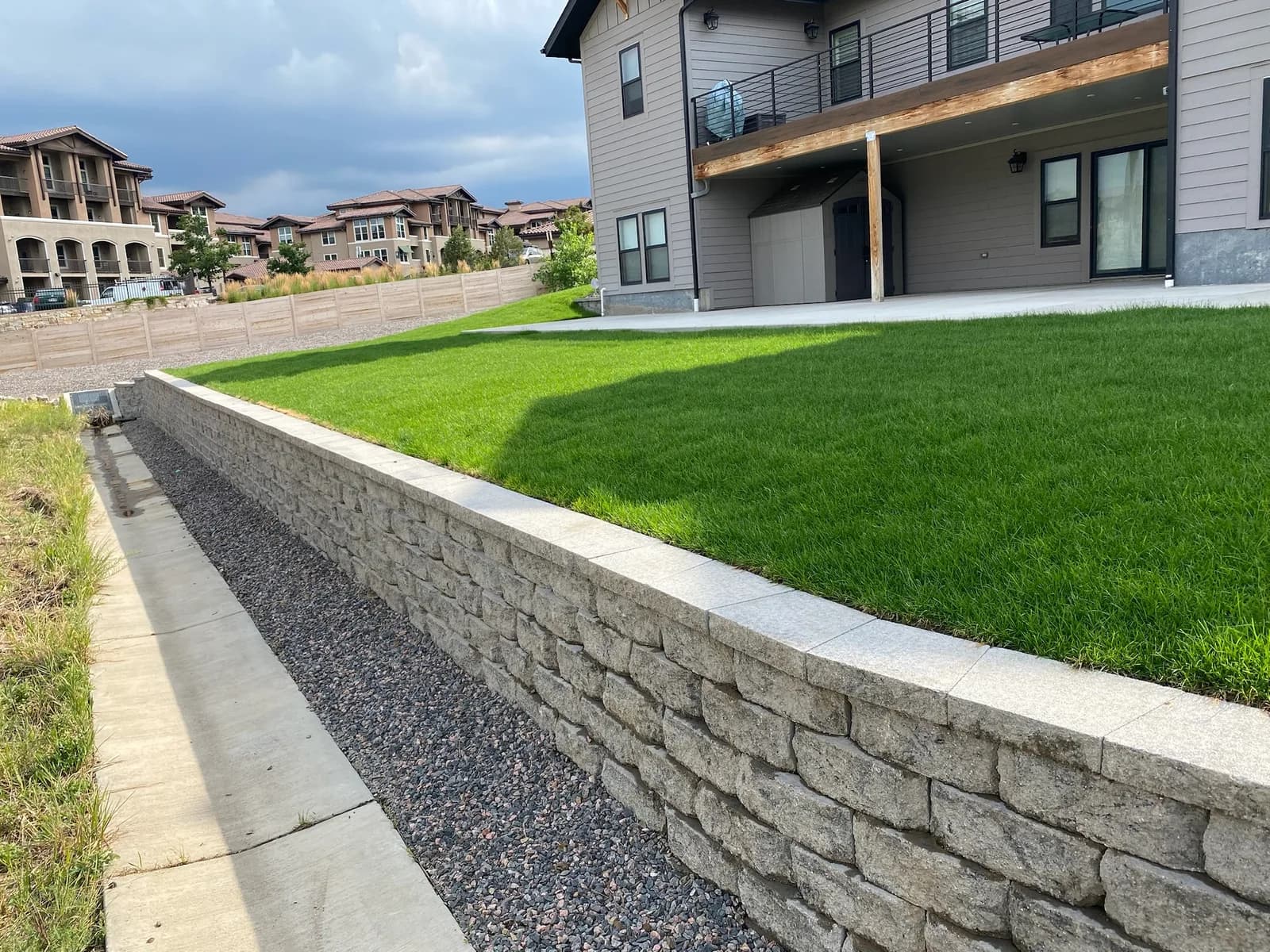 Stacked-block retaining wall supporting a raised, freshly sodded lawn