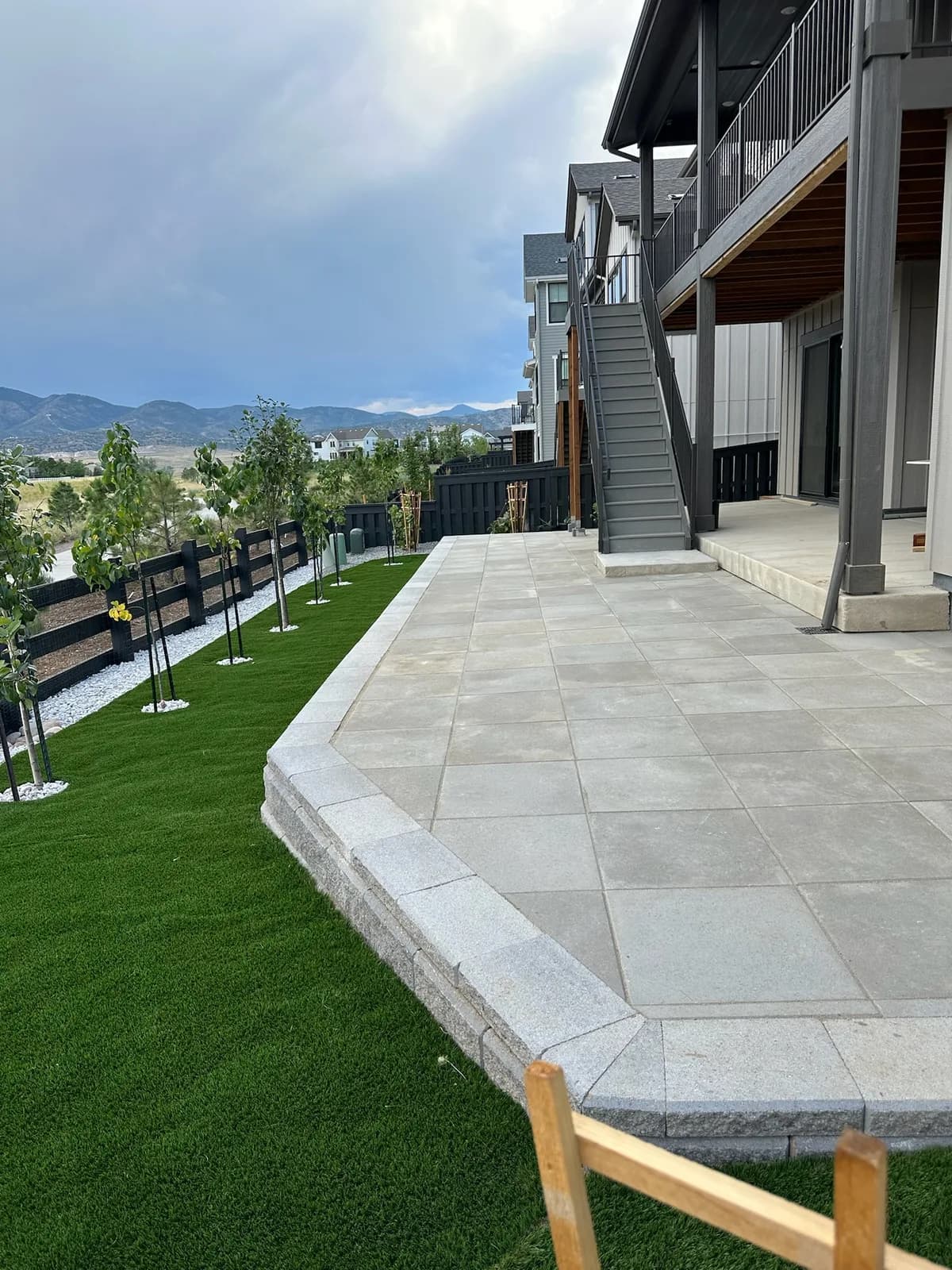 Backyard lawn beside a paver patio, enclosed by fencing with a mountain backdrop