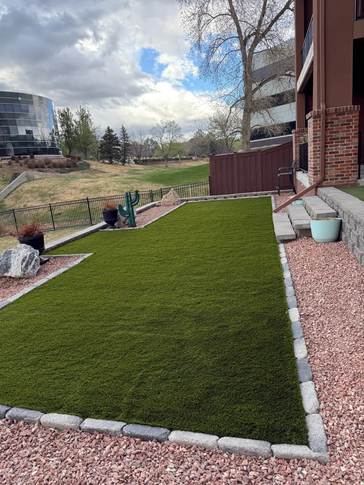 Narrow side-yard lawn strip edged with river rock and a paver band